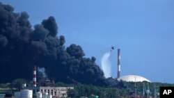 Un helicóptero derrama agua de mar sobre uno de los tanques incendiados. Los bomberos cubanos, junto a técnicos y especialistas de México y Venezuela, intentaban sofocar las llamas este domingo. (AP/Ramon Espinosa)