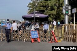 Un agente de policía hace gestos a un periodista para que se detenga en un puesto de seguridad en una calle cerca de la Plaza de Tiananmen, en Beijing, en el 34to aniversario de las protestas prodemocracia. (AP/Andy Wong)