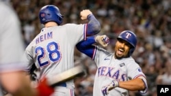 Marcus Semien (der.) festeja su jonrón de tres carreras junto a Jonah Heim, su compañero en los Rangers de Texas, en el cuarto juego de la Serie Mundial ante los Diamondbacks de Arizona. (AP Foto/Brynn Anderson)