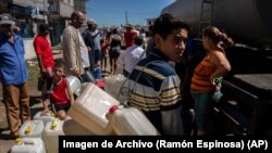 Personas hacen fila frente a un camión cisterna que distribuye agua potable tras el paso del huracán Ian en La Coloma, Pinar del Río 