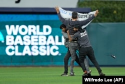 Danilo Maldonado "El Sexto" es detenido por guardias de seguridad del estadio LoanDepot, en Miami, tras lanzarse al terreno con un cartel. (AP/Wilfredo Lee)