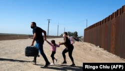 Una familia de migrantes cubanos se apresura a cruzar la frontera en Yuma, Arizona, en mayo de 2021. (Ringo Chiu/ AFP)