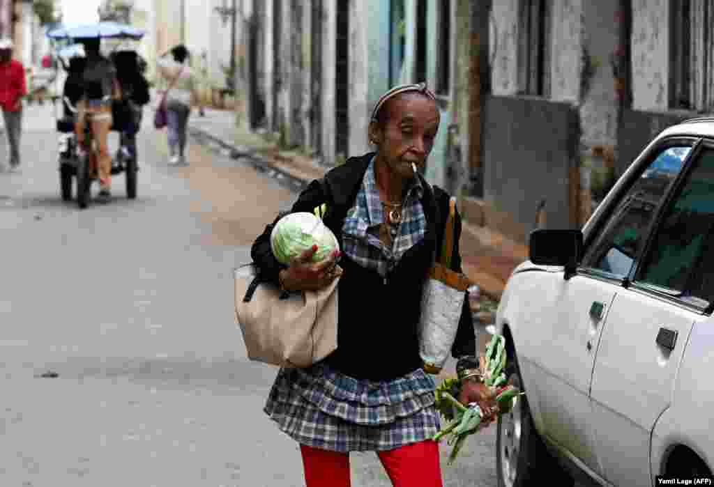 Una mujer carga verduras mientras camina por una calle de La Habana, el 20 de diciembre de 2023.