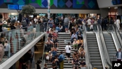 Viajeros sentados en las escaleras de la estación Gare de Montparnasse, el día de la inauguración de los Juegos Olímpicos de París, el viernes 26 de julio de 2024 en París, Francia. (AP Foto/Yasin Dar)
