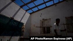 Un voluntario limpia un aula sin techo en una escuela gravemente dañada por el huracán Ian, en La Coloma, Pinar del Río. (AP Foto/Ramón Espinosa)