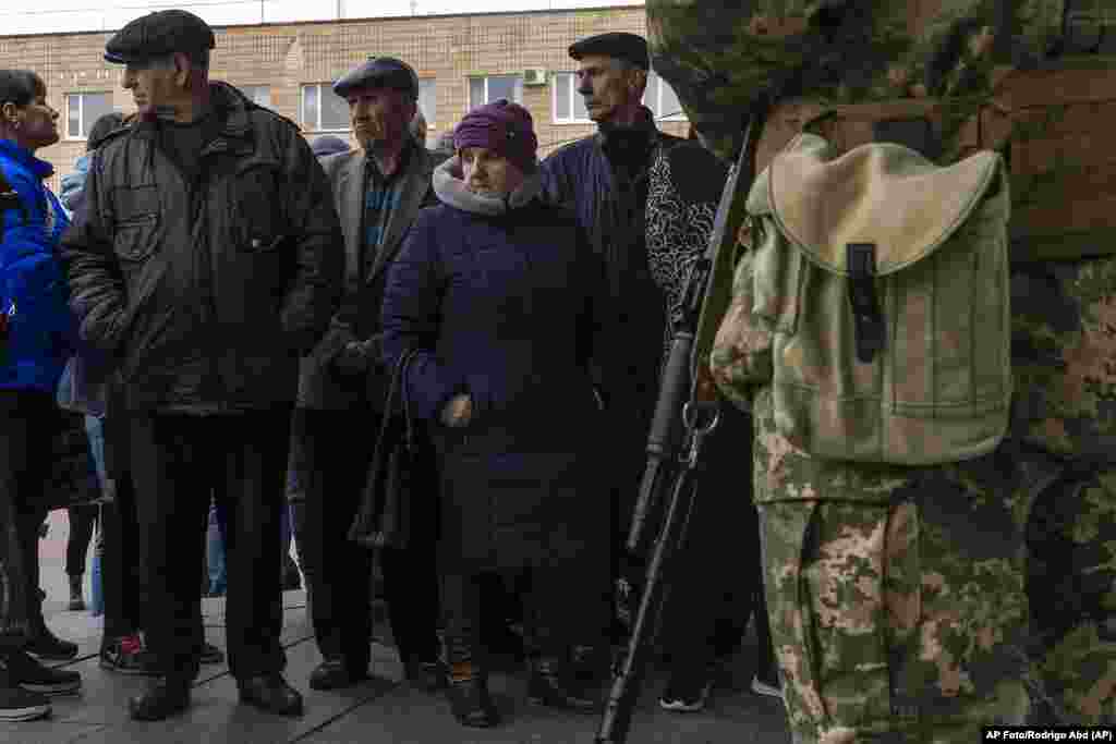 Personas desplazadas esperan en fila frente al Departamento de Distrito del Servicio Estatal de Migración el martes 29 de marzo de 2022, para recibir alimentos y un lugar para dormir, en Brovary, en las afueras de Kiev, Ucrania. (AP Foto/Rodrigo Abd)