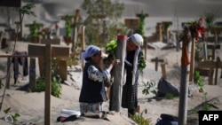 Mujeres uigures decoran una tumba en las afueras de Hotan, en la región de Xinjiang (Foto: AFP).