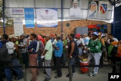 Una interminable fila de personas que esperan al sol durante horas para recibir un plato de comida.