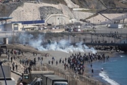 Las fuerzas de seguridad españolas lanzan gases lacrimógenos contra migrantes marroquíes y subsaharianos que intentan cruzar la valla del enclave español de Ceuta, el miércoles 19 de mayo de 2021.