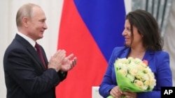 El presidente de Rusia, Vladimir Putin, aplaude a Margarita Simonyan, directora del medio de comunicación ruso RT, tras otorgarle la Orden de Alejandro Nevsky durante una ceremonia en el Kremlin en Moscú el 23 de mayo de 2019. (© Mikhail Klimentyev/Sputnik/Kremlin/AP Images)