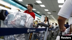 Cubanos cargados de equipaje hacen fila en el Aeropuerto Internacional de Miami para viajar a la isla. (REUTERS/Carlos Barria/Archivo)