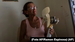 Miriam Cortés posa con su ventilador durante un apagón matutino programado, en su casa de Regla, Cuba, el lunes 1 de agosto de 2022.