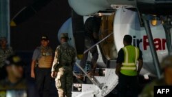 Un migrante colombiano, esposado de pies y manos, sube a un avión en el aeropuerto de Albrook Gelabert, en Ciudad de Panamá, el 20 de agosto de 2024, durante su deportación.