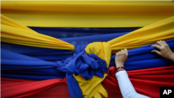 Un partidario de la oposición sostiene una tela con los colores de la bandera venezolana antes de un mitin con el líder opositor Juan Guaidó en el Montalbán de Caracas. Enero 11, 2021. Foto: AP