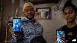 Emilio Román (izquierda) y su nuera María Carla Milán Ramos (derecha) muestran imágenes de familiares arrestados el 11 de julio en La Güinera, La Habana. (AP Photo/Ramón Espinosa).