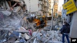 Rescatistas utilizan una excavadora para retirar escombros de edificios destruidos en el lugar de un ataque aéreo israelí el domingo por la noche arias oficinas de entidades financieras de Hezbollah Beirut, Líbano. (AP/Hassan Ammar)