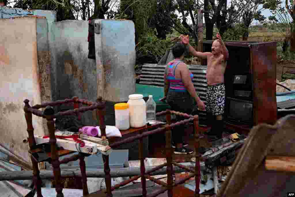 A couple talks among the debris of a house after the passage of hurricane Rafael in Alquizar, Artemisa province, Cuba on November 7, 2024.