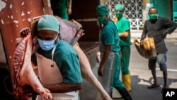 Trabajadores se protegen con máscaras del contagio del coronavirus. AP Photo/Ramon Espinosa