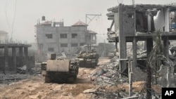 En esta imagen sin fecha distribuida por el ejército israelí, vehículos blindados de transporte de tropas avanzan entre edificios destruidos durante una operación terrestre en la Franja de Gaza, (Fuerzas de Defensa de Israel vía AP)