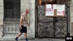 Foto Archivo. un hombre cerca de un cartel que anuncia elecciones municipales en Cuba.