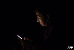 Una mujer usa su teléfono celular el lunes en Caracas, en medio del apagón que dejó sin luz a buena parte de la capital y más de la mitad del país (Foto: AFP).