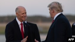 El presidente Donald Trump (der) saluda al senador por la Florida Rick Scott. (Archivo, AFP).