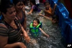 Los niños disfrutan el tractor piscina en El Infernal, en la provincia de Pinar del Río, Cuba. (AP Foto/Ramon Espinosa)