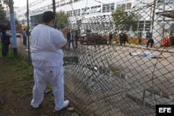 Un trabajador del hospital Roosevelt toma la escena donde murieron dos hombres frente al Hospital Roosevelt de Guatemala.