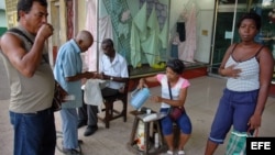  Varias personas toman café en el portal de una tienda, en La Habana, Cuba.