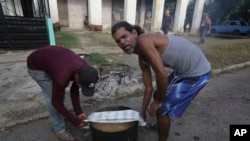 Residentes llevan una olla de caldosa para compartir con los vecinos después del paso del huracán Rafael por La Habana, el 7 de noviembre de 2024. (Foto AP/Ariel Ley)