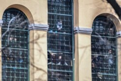 En esta foto tomada el 9 de marzo, un grupo de reos de la cárcel San Vittore, de Milán, tratan de llamar la atención desde las ventanas del reclusorio en medio de una protesta por la cuarentena del coronavirus (Foto: Miguel Medina/AFP).