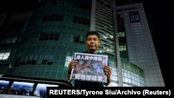 El fotógrafo Harry Long, del desaparecido periódico Apple News, muestra la primera plana de la última tirada frente a la sede del diario en Hong Kong el 24 de junio de 2021. Foto: REUTERS/Tyrone Siu/Archivo