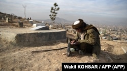 Un hombre lee el Corán junto a la tumba de un familiar en un cementerio en las afueras de Kabul, Afganistán, el 14 de enero de 2021. Foto Archivo: Wakil KOHSAR / AFP.