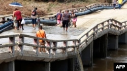 La gente cruza un puente afectado días después del paso del huracán Oscar en Guantánamo, Cuba, el 29 de octubre de 2024.