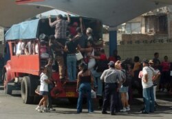 Varias personas intentan subir a un camión particular que funciona como transporte público