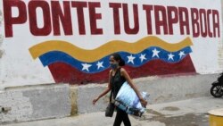 Una mujer pasa junto a un cartel que llama al uso de la máscara como protección contra el coronavirus. (AP/Matias Delacroix)