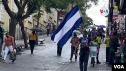 Un joven nicaragüense sostienen una bandera de Nicaragua mientras camina por una calle en San José, el 20 de septiembre de 2021.