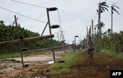 Un hombre monta su bicicleta junto a cables eléctricos caídos tras el paso del huracán Rafael en Guira de Melena, provincia de Artemisa, Cuba, el 7 de noviembre de 2024.