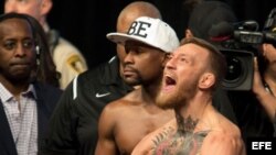 El campeón de la UFC, Conor McGregor (d) reacciona junto al boxeador estadounidense Floyd Mayweather (c).