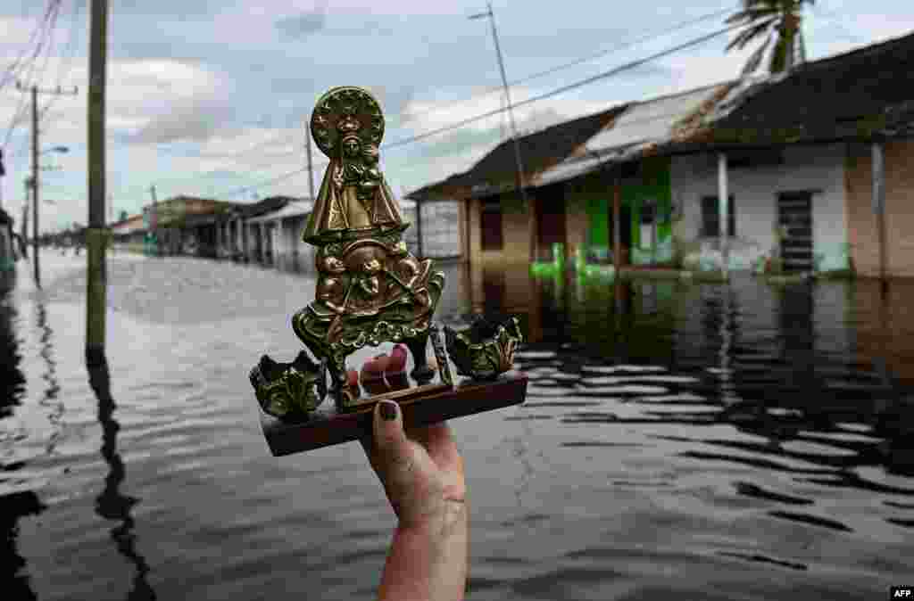 Una mujer sostiene una imagen de la Virgen de la Caridad del Cobre mientras ocurren inundaciones en Batabanó.