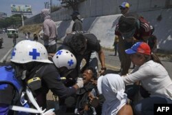 Un manifestante afectado por gas lacrimógeno es asistido durante un enfrentamiento con soldados bolivarianos en Caracas.