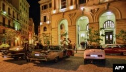 Autos antiguos en las afueras de un edificio de La Habana.