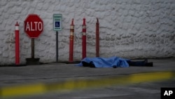 Un cuerpo yace cubierto con una lona en el suelo en Culiacán, estado de Sinaloa, México, el jueves 19 de septiembre de 2024. (Foto AP/Eduardo Verdugo)