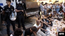 Manifestantes turcos comen en frente a policías antidisturbios,9 de julio de 2013, durante protesta antigobierno el primer día del Ramadan en Estambul (Turquía).