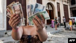 Una mujer muestra pesos cubanos (CUP) y pesos convertibles (CUC). AFP