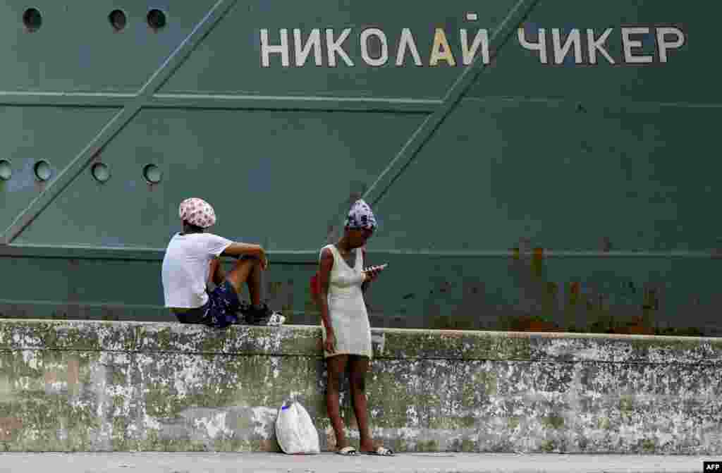 Personas permanecen frente al remolcador de rescate y salvamento Nikolai Chiker, parte del destacamento naval ruso que visita Cuba, tras su llegada al puerto de La Habana el 12 de junio de 2024.&nbsp;YAMIL LAGE / AFP