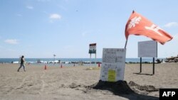 Una bandera roja ondea al viento mientras las autoridades advierten no nadar en una playa en Hiratsuka, al suroeste de Tokio, tras el "aviso de megasismo" del gobierno. (Foto: JIJI PRESS / AFP) 