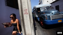 Una joven camina cerca de un camión de transporte de pasajeros en la ciudad de Santiago de Cuba.