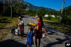 Dainet Cala y su hija Evelyn llevan flores para dejarlas como ofrenda en el santuario de la Virgen de la Caridad del Cobre en El Cobre, en febrero de 2024. AP/Ramón Espinosa