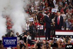 El expresidente de los Estados Unidos y candidato presidencial republicano para 2024, Donald Trump, estrecha la mano del senador estadounidense y candidato republicano a la vicepresidencia para 2024, J.D. Vance, en la Universidad Estatal de Georgia. CHRISTIAN MONTERROSA / AFP